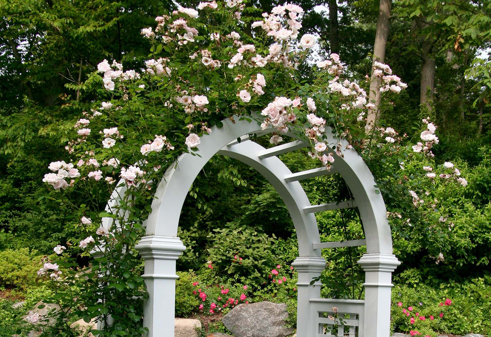Decorative arbor with picket fence and bluestone walkway.