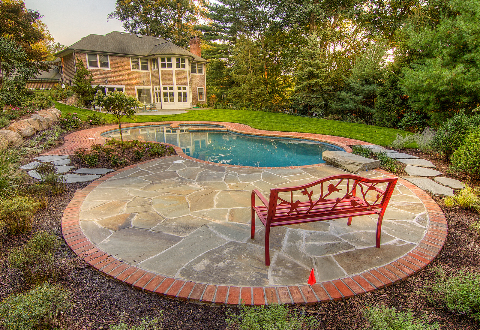 Secluded gunite pool and spa surrounded by a bluestone patio with brick coping.